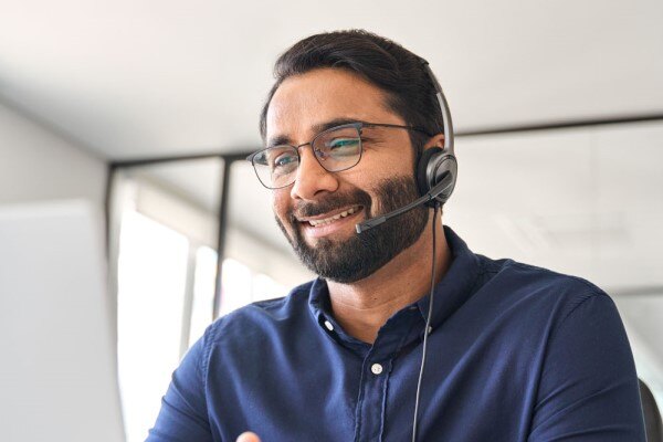 A smiling man wearing a headset on a video call